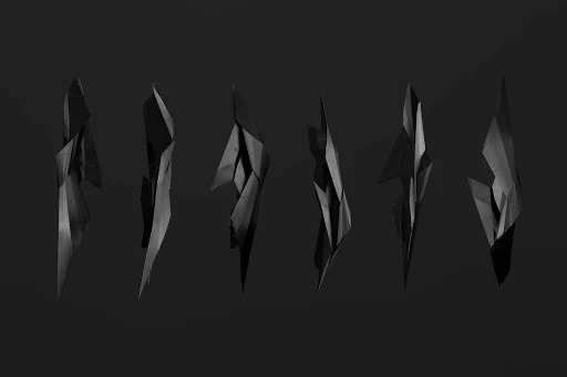Monochromatic still life features six abstract, jagged, geometric sculptures against a seamless dark backdrop with dramatic studio lighting.