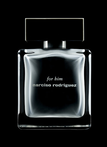 Rectangular glass perfume bottle with dark liquid and bold black cap against a pitch black background
