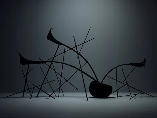 Dark botanical arrangement in a round vessel supported by slender geometric sticks against a plain grey gradient background.