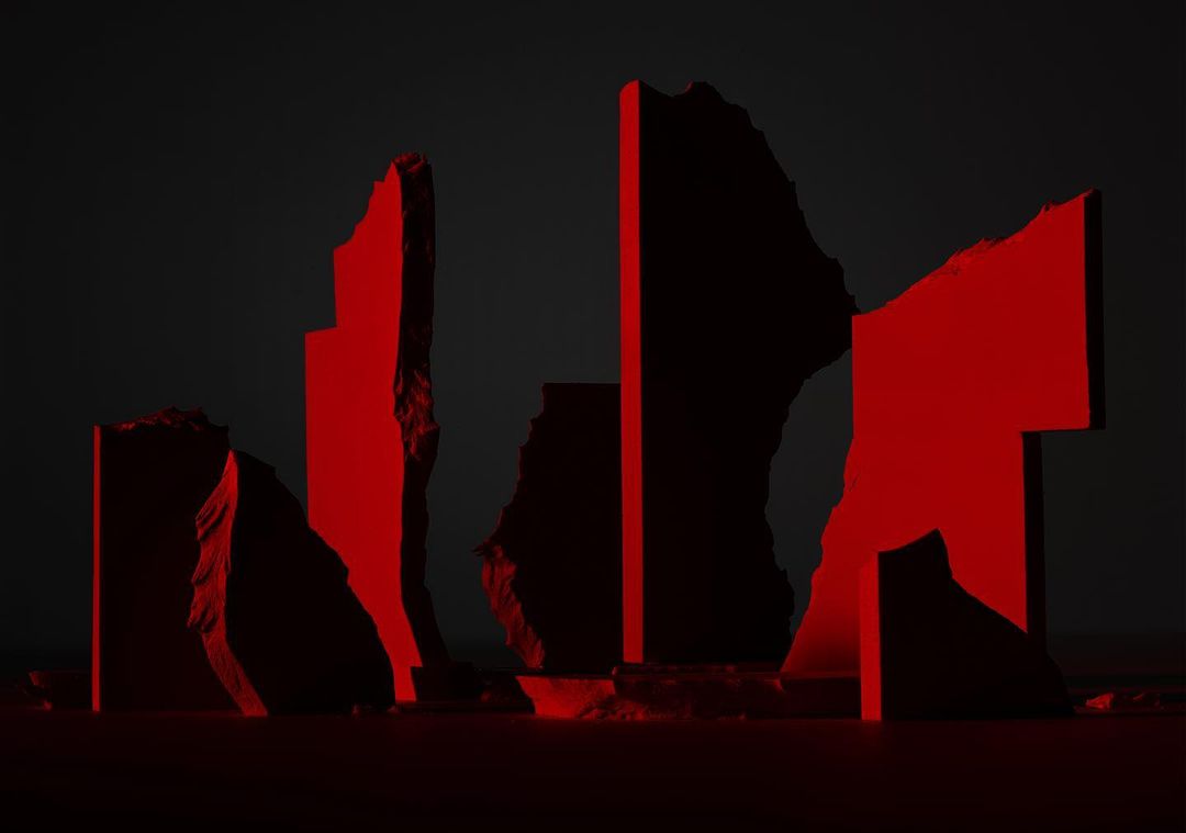 Abstract rock formation against a dark background, illuminated by red lighting, creating a stark contrast and dramatic visual effect.