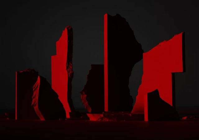 Abstract rock formation against a dark background, illuminated by red lighting, creating a stark contrast and dramatic visual effect.