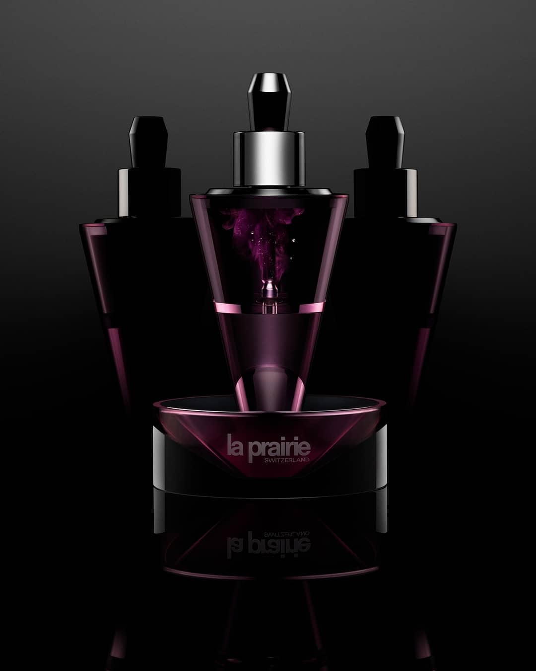 Three La Prairie skincare products sit in a close-up studio shot with a dark background and strong lighting to highlight the product details.