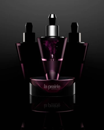 Three La Prairie skincare products sit in a close-up studio shot with a dark background and strong lighting to highlight the product details.