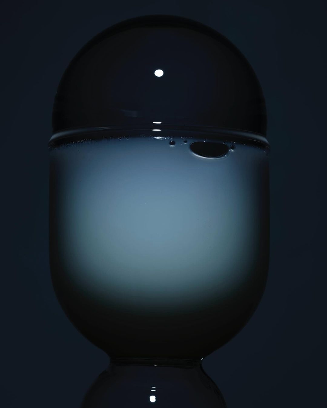 Crystal ball sits atop a pedestal, its translucent surface reflecting a soft, diffused light against a dark backdrop.