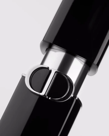 Extreme close up of a black and silver lipstick tube featuring the prominent Christian Dior CD logo against white