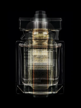 Luxury perfume bottle featuring both Chanel and Miss Dior branding with overlapping translucent glass design on a stark black backdrop.