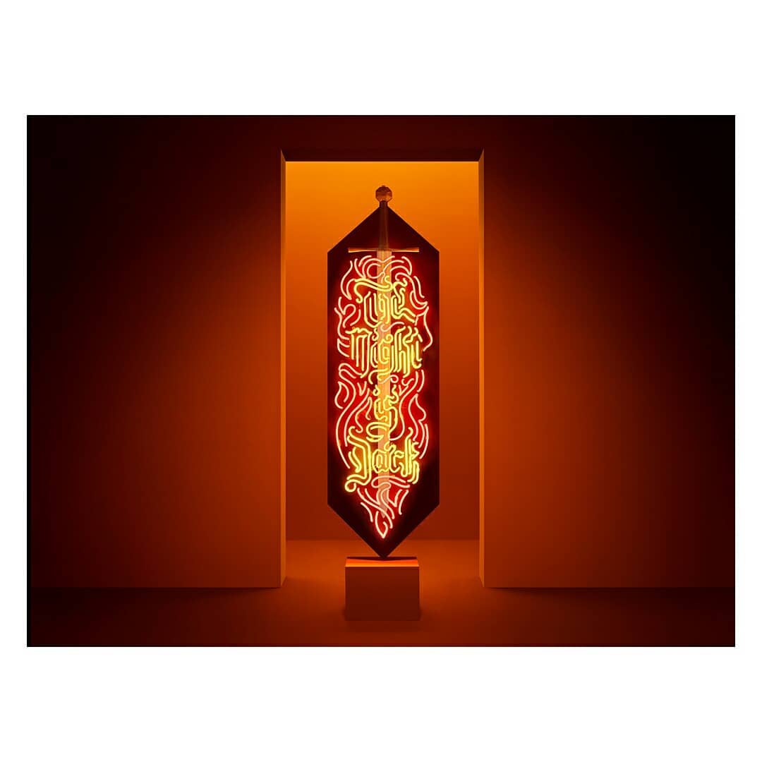 Neon light art sign with the words 'The Night is Jack' against a white wall and doorway with warm orange-yellow backlight glow.