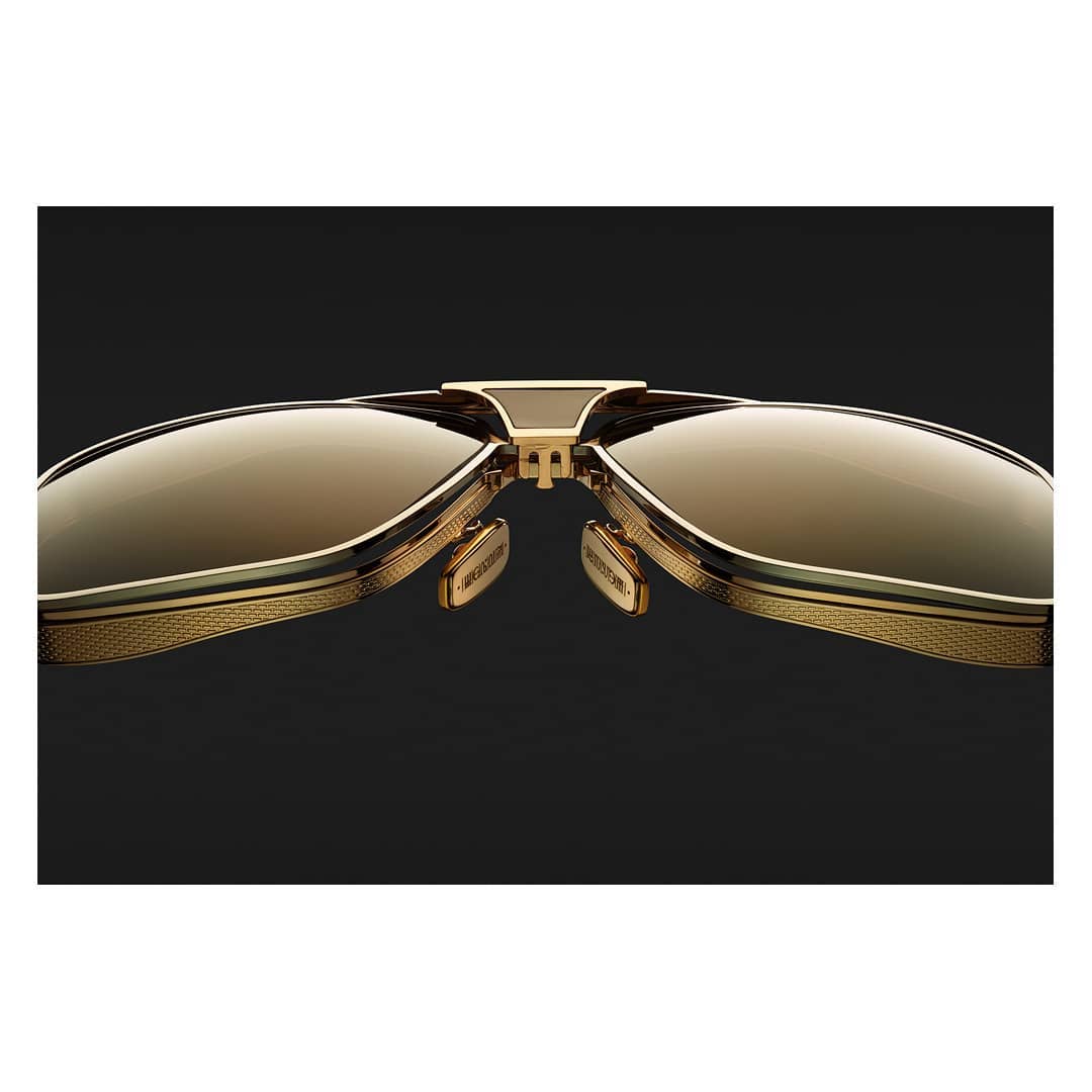 Close-up studio shot of stylish gold-framed sunglasses with reflective brown lenses, showcasing high-end eyewear design and craftsmanship.