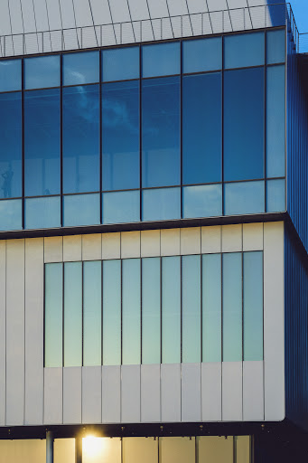 Exterior view of modern building with blue-tinted windows and white concrete facade in architectural photography showcasing natural light.