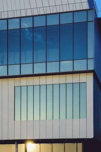 Exterior view of modern building with blue-tinted windows and white concrete facade in architectural photography showcasing natural light.