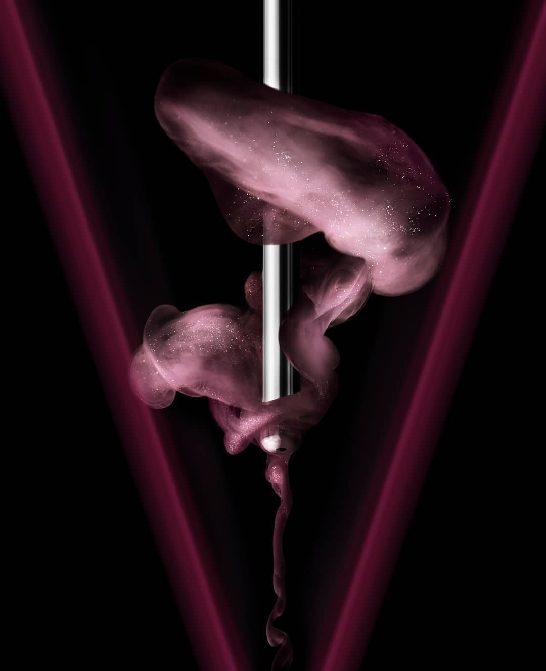 Abstract art featuring pink fluid suspended around a silver pole against a black background with soft V-shaped red light.