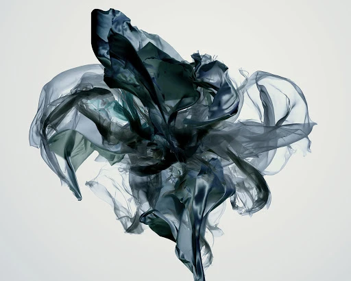 Abstract image featuring flowing, translucent fabric in shades of teal and grey, creating a dynamic and airy composition against a white background.