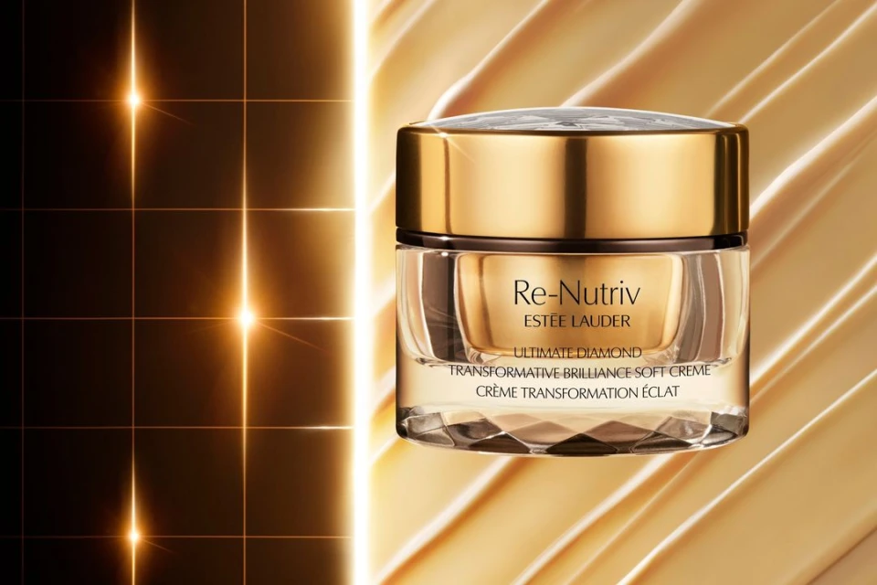 Close-up of Re-Nutriv Estee Lauder Ultimate Diamond transformative cream with a gold lid and glossy golden liquid background.