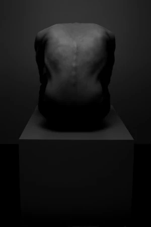 Monochrome portrait from behind of a person crouched on a block in deep shadow
