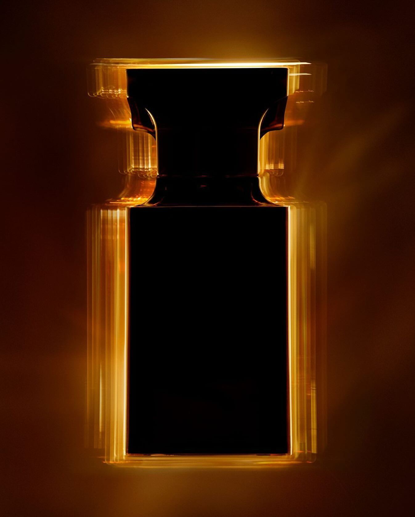 Studio shot of a black rectangular perfume bottle outlined with amber light, creating a sleek and modern aesthetic on a brown background.