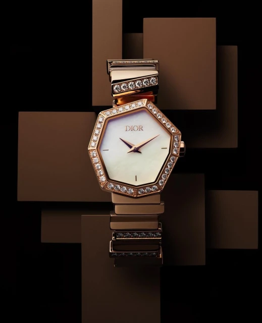 Luxury Dior wristwatch with gold band and diamond bezel on a brown geometric background. Elegant time piece is a statement accessory.