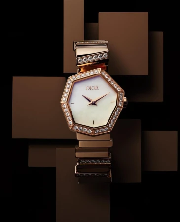 Luxury Dior wristwatch with gold band and diamond bezel on a brown geometric background. Elegant time piece is a statement accessory.