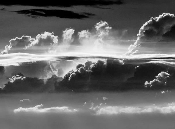 Dramatic monochrome cloudscape fills the frame with swirling formations, creating a textured, atmospheric skyscape with high contrast.