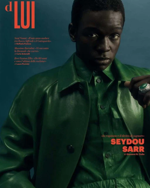 Magazine cover featuring Seydou Sarr, an adult male of African descent, wearing green clothing, accessorized with a statement ring. Portrait.