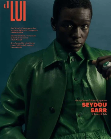 Magazine cover featuring Seydou Sarr, an adult male of African descent, wearing green clothing, accessorized with a statement ring. Portrait.