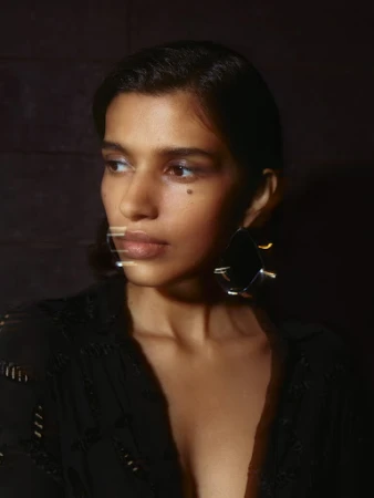 Portrait of a woman wearing a black top and statement earring, photographed by Nicolas Kern.