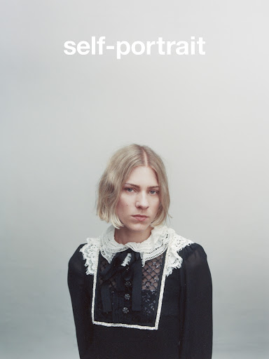 Blonde woman in a vintage black dress with lace collar, posing against a light grey background. Close-up studio portrait with bright light.