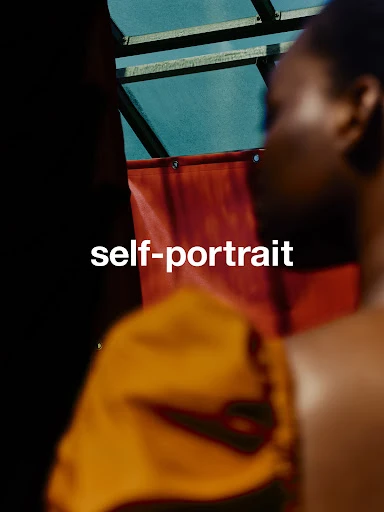 Portrait of a blurred woman in an orange top, backlit by light coming from a turquoise pane, and the words "self-portrait" in white.