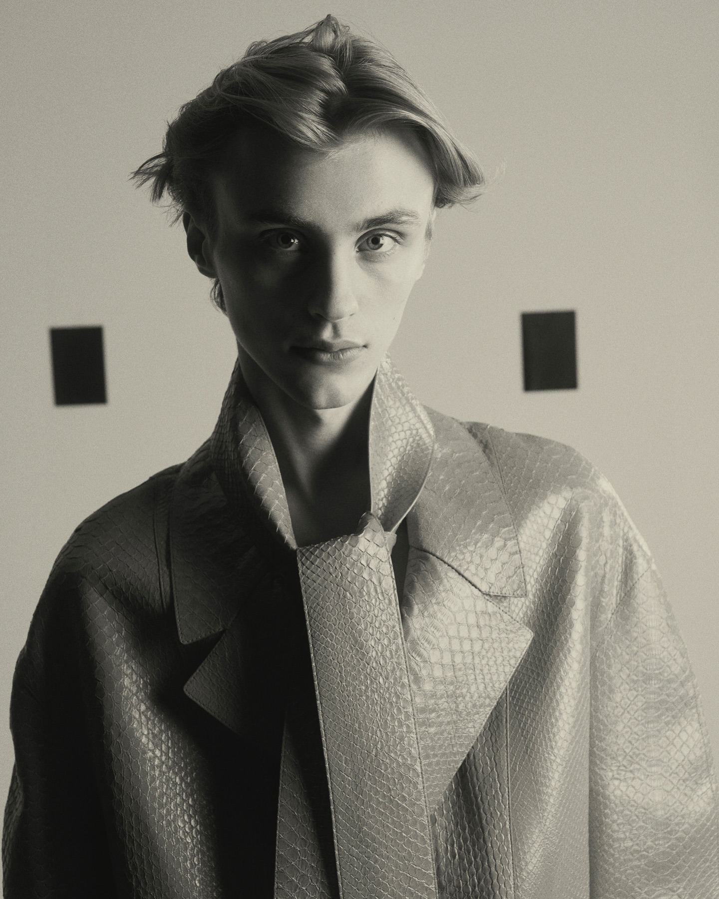 Portrait of a young man with parted blonde hair wearing a textured patterned coat photographed by Nicolas Kern.