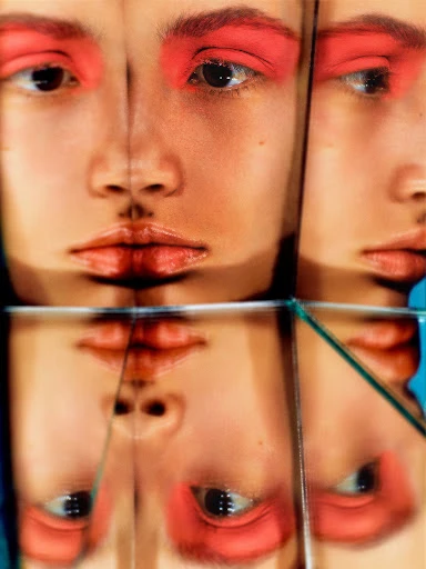 Close-up studio portrait of an adult female face with a red eyeshadow makeup effect, fragmented into geometric mirrored glass tiles.