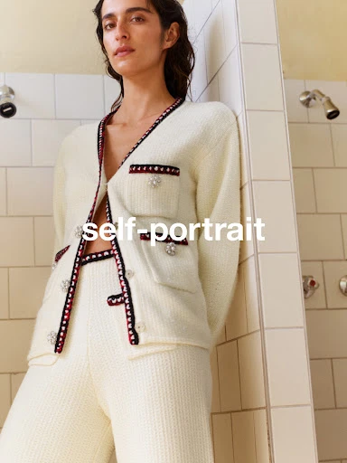 A woman in a cream-colored knit cardigan and pants leans against a tiled wall, with the brand name 'self-portrait' overlaid.
