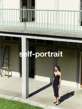 Woman in a black dress standing on a concrete walkway outside a building photographed by Nicolas Kern.