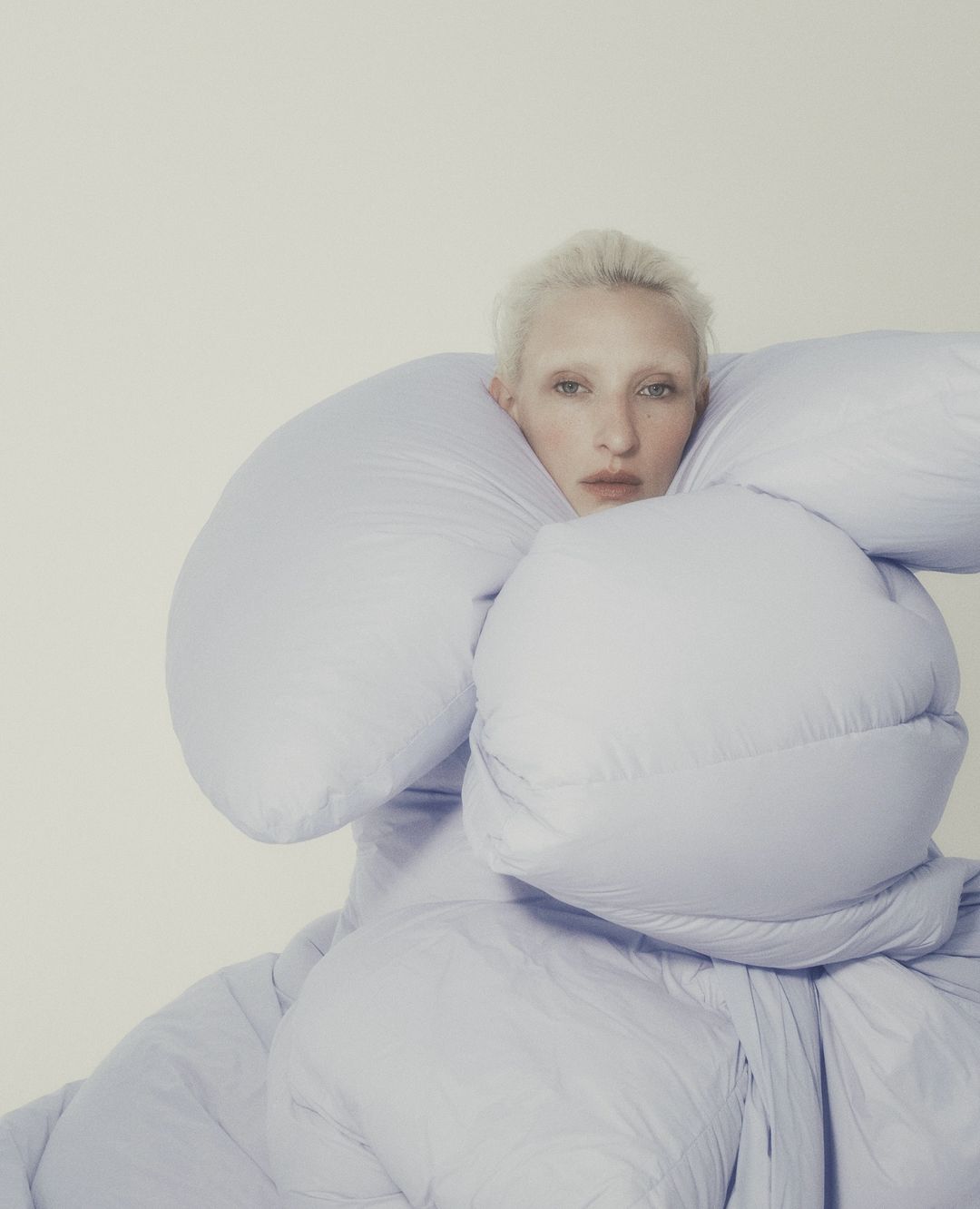 Model with bleached hair wrapped tightly inside voluminous pale blue padded outerwear