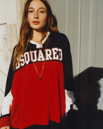 Woman wearing a color-blocked long-sleeve athletic jersey and gold chain necklace outdoors in sunlight