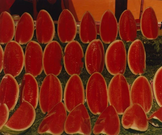 Rows of sliced watermelons on display, showcasing their vibrant red flesh and green rinds, neatly arranged and ready to eat.