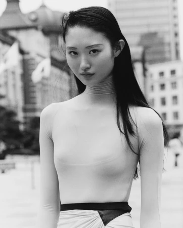 Monochrome portrait of an East Asian woman with long dark hair wearing a fitted top and high-waisted skirt outdoors in Paris