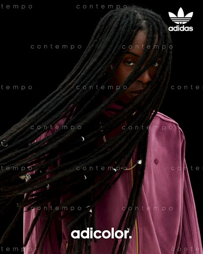 Adidas ad featuring a woman with dreadlocks wearing a purple jacket against a dark background, showcasing fashion and style elements.