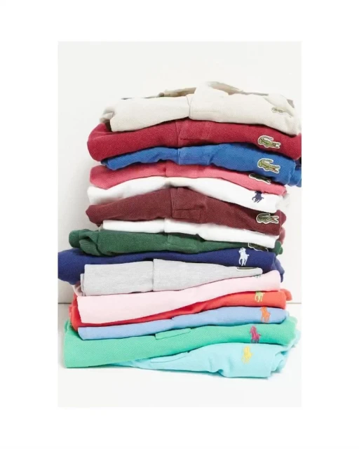 Stack of colorful polo shirts with brand logos, including Lacoste and Ralph Lauren, on a white background, clean and neatly folded.