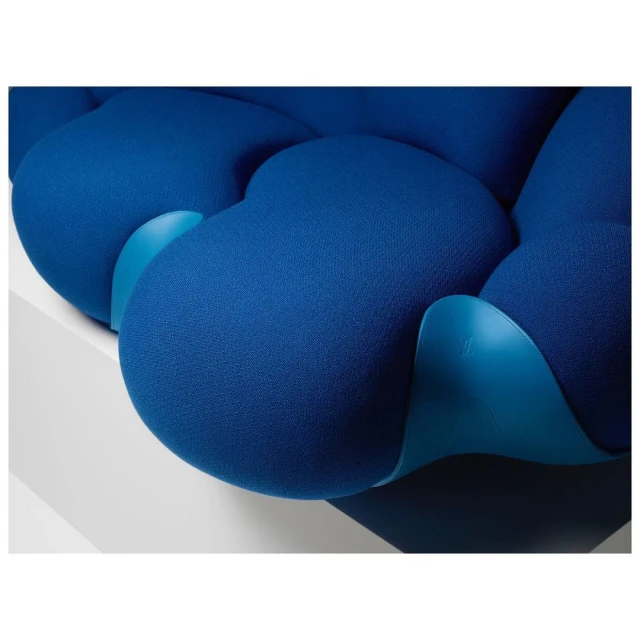 Close-up of a blue upholstered lounge chair featuring a segmented design and supported by a light blue frame, set against a white backdrop.