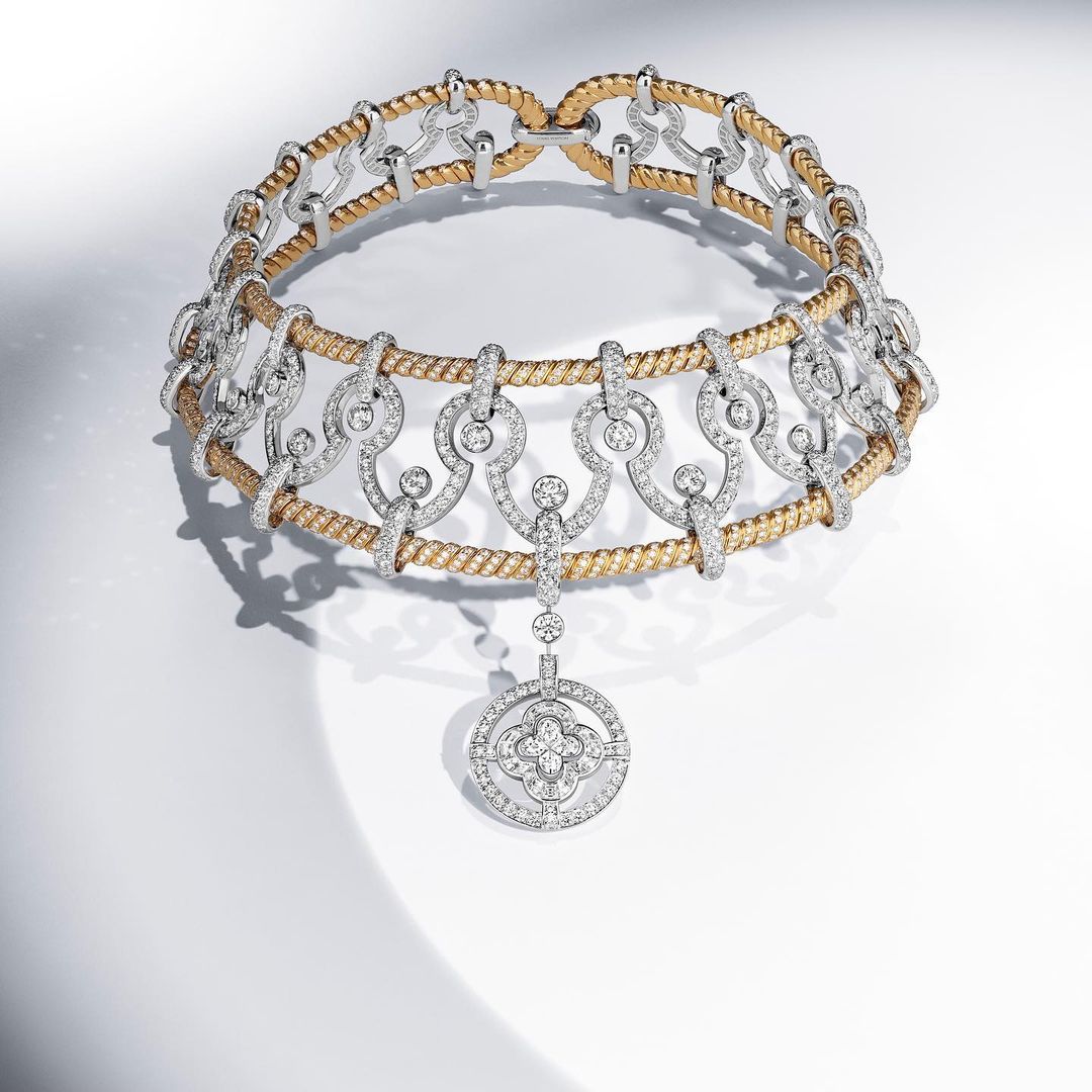 Elegant gold and silver necklace featuring intricate diamond detailing and pendant, showcasing luxury jewelry design on a bright background.