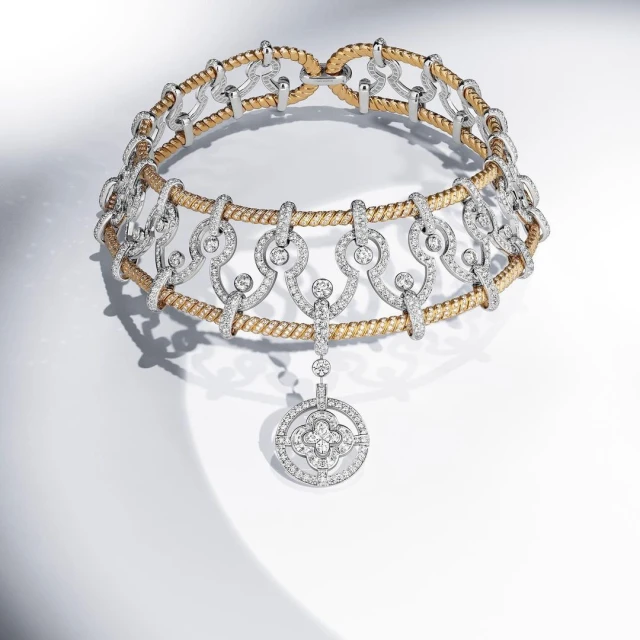 Elegant gold and silver necklace featuring intricate diamond detailing and pendant, showcasing luxury jewelry design on a bright background.