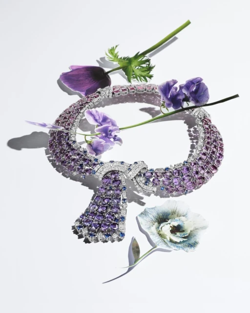 Exquisite amethyst and diamond necklace surrounded by delicate purple and blue flowers, set against a stark white background.