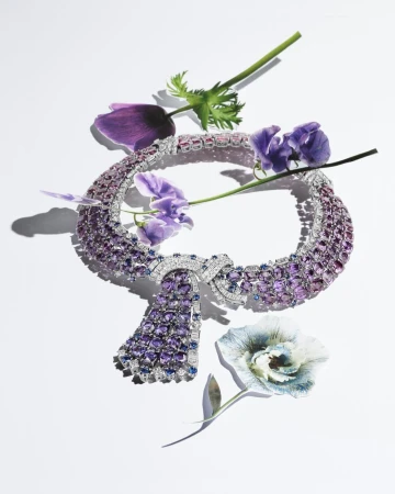 Exquisite amethyst and diamond necklace surrounded by delicate purple and blue flowers, set against a stark white background.