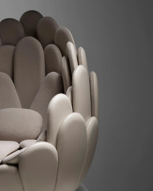 Close-up of a beige-toned armchair, showcasing its unique petal-like design and textures, against a simple grey background.