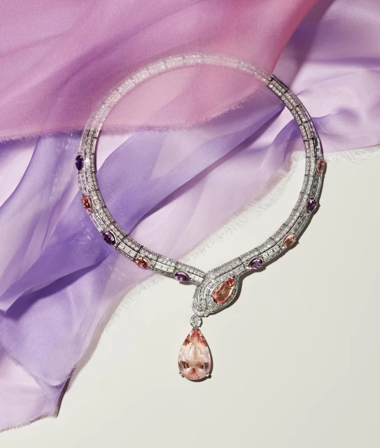 Elegant necklace with gemstones and diamonds on draped purple silk fabric, jewelry still life, studio lighting, luxury fashion accessory.