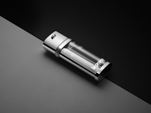 La Prairie anti-aging cream lies diagonally on gray and black split surface, studio lit, product shot for beauty and skincare.