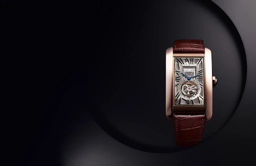 Elegant close-up studio shot of a rose gold Cartier Tank watch with a brown leather band against a dark, contrasting background.