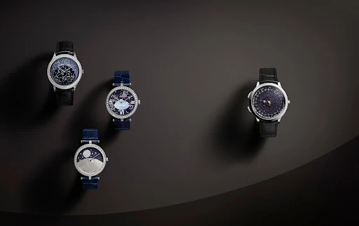 Four luxury wristwatches with diamond bezels, blue and black leather straps, and decorative dials on a gradient grey background.