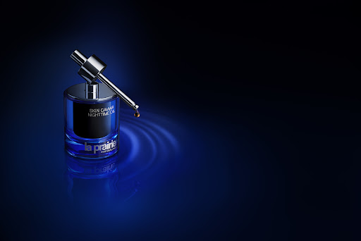 Close-up studio shot of La Prairie Skin Caviar Nighttime Oil, showcasing its sleek blue bottle and silver dropper against a dark backdrop.