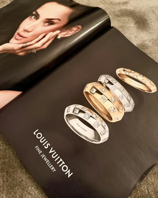 Close-up of a Louis Vuitton jewelry advertisement featuring fine jewelry rings on a black background, showcasing an adult female model's face.