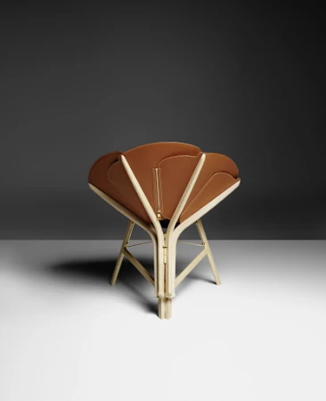 Tan folding chair with beige wood frame against a dark gray and white gradient background. Modern furniture design with unique style.